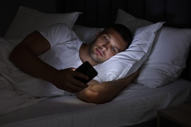 Bad habit. Man using smartphone in bed at night