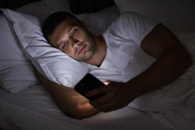 Bad habit. Man using smartphone in bed at night