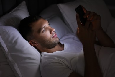 Bad habit. Man using smartphone in bed at night