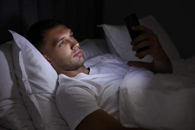 Bad habit. Man using smartphone in bed at night