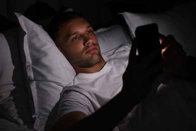 Bad habit. Man using smartphone in bed at night