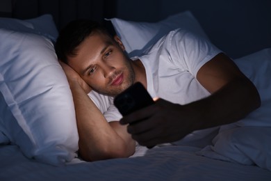 Bad habit. Man using smartphone in bed at night