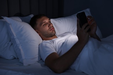 Bad habit. Man using smartphone in bed at night