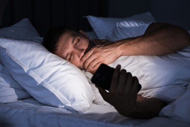 Bad habit. Man using smartphone in bed at night