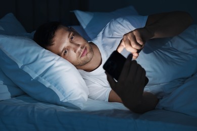 Bad habit. Man using smartphone in bed at night