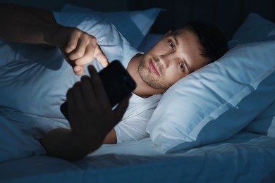 Bad habit. Man using smartphone in bed at night