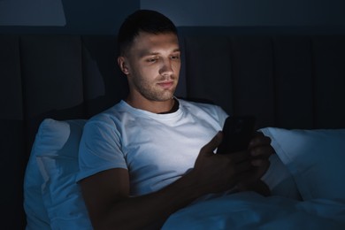 Bad habit. Man using smartphone in bed at night