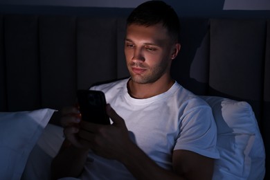 Bad habit. Man using smartphone in bed at night