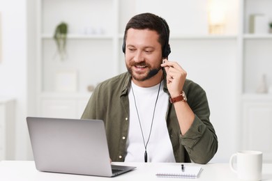 Interpreter in headset having video chat via laptop at white table indoors