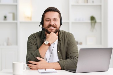 Interpreter in headset having video chat via laptop at white table indoors