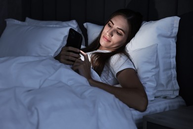 Bad habit. Young woman using smartphone in bed at night