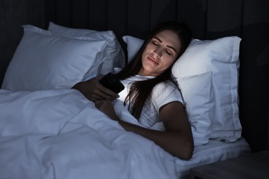 Bad habit. Young woman using smartphone in bed at night