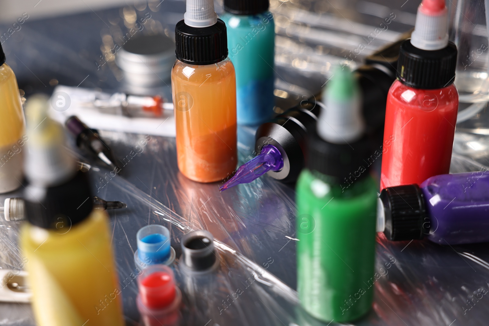 Photo of Tattoo machine and colorful inks on table, closeup