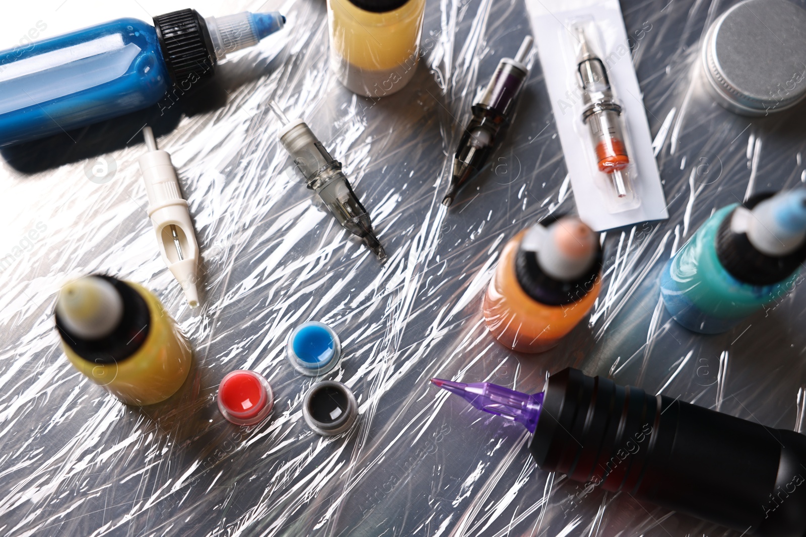 Photo of Tattoo machine and colorful inks on table, above view