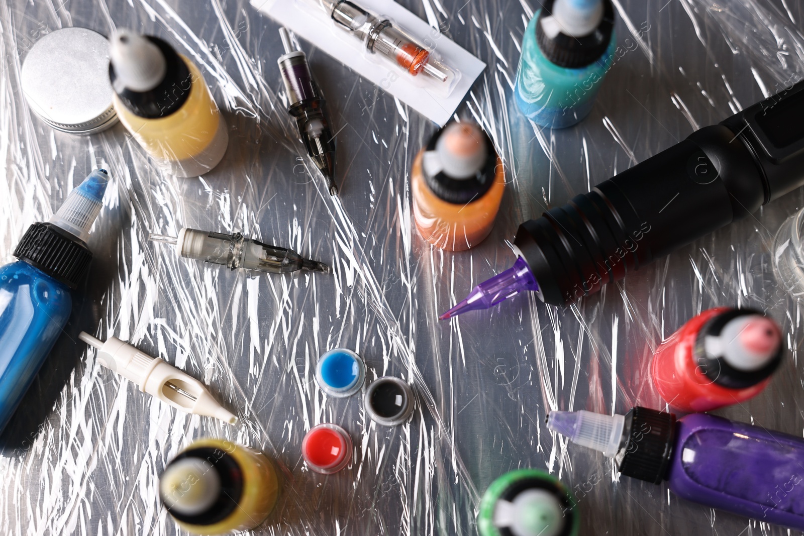 Photo of Tattoo machine and colorful inks on table, above view