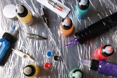 Tattoo machine and colorful inks on table, above view