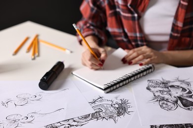 Photo of Tattoo artist drawing sketch with pencil at white table, closeup