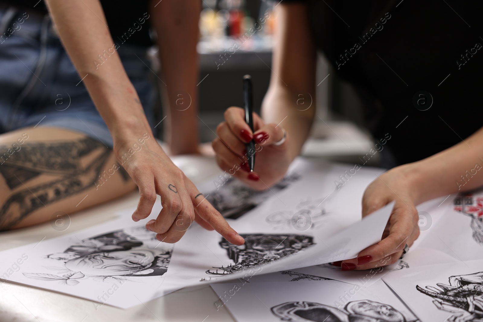 Photo of Tattoo artist showing sketch to client in salon, closeup