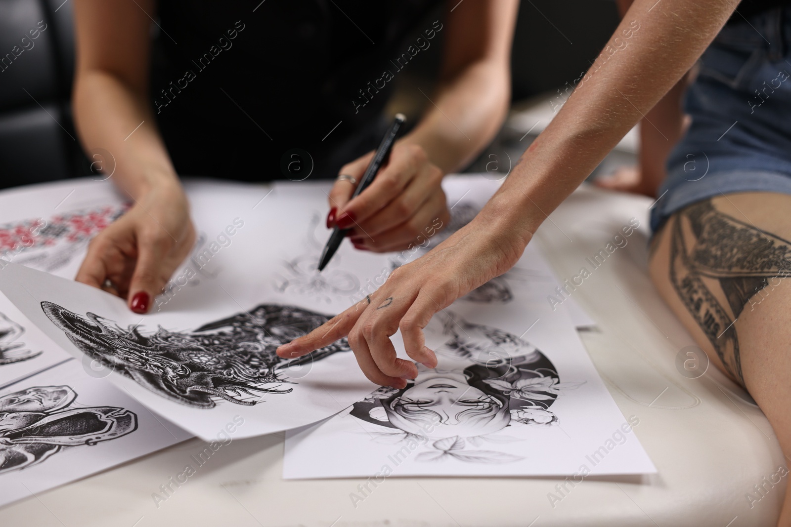 Photo of Tattoo artist showing sketch to client in salon, closeup