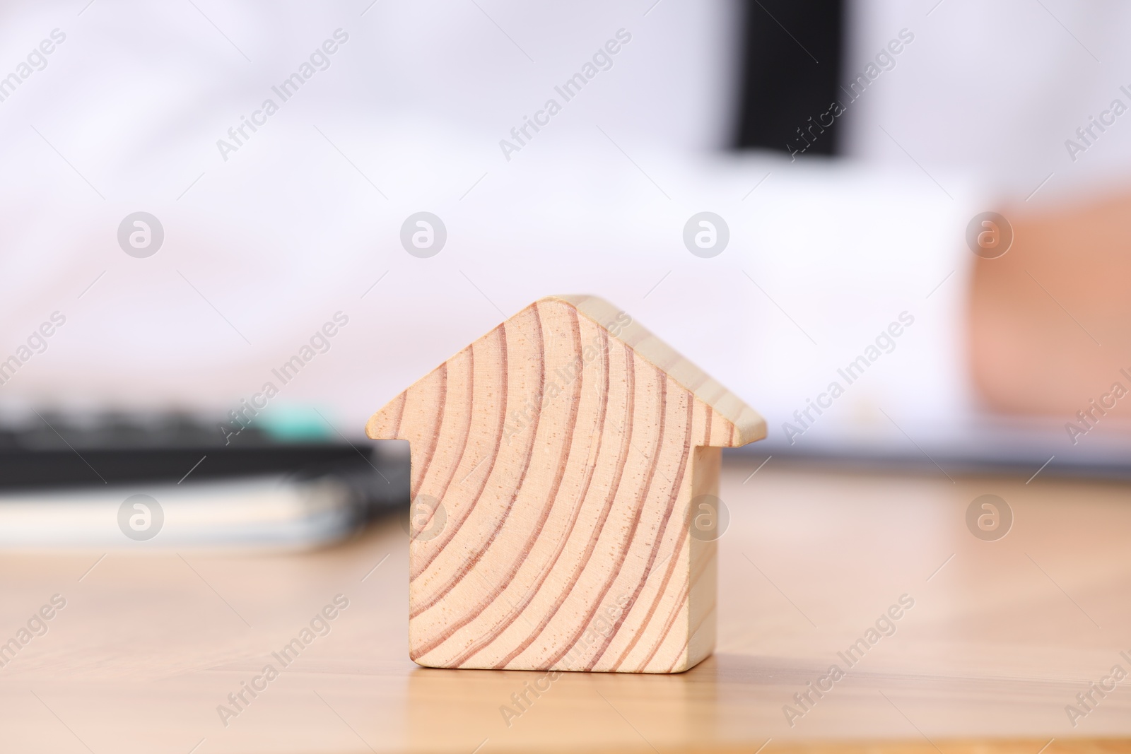 Photo of Property insurance. Real estate agent working at table indoors, focus on wooden house figure