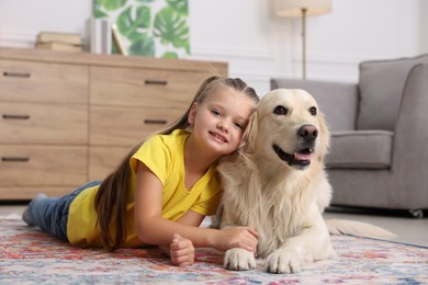 Girl with cute Golden Retriever dog lying on rug at home