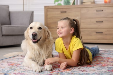 Photo of Girl with cute Golden Retriever dog lying on rug at home