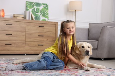 Girl with her cute Golden Retriever dog on rug at home