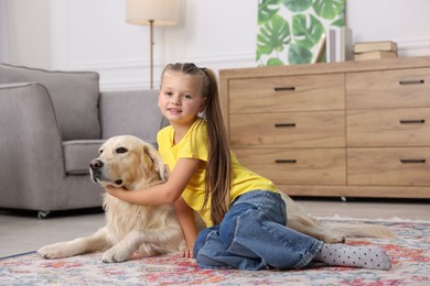 Girl with her cute Golden Retriever dog on rug at home