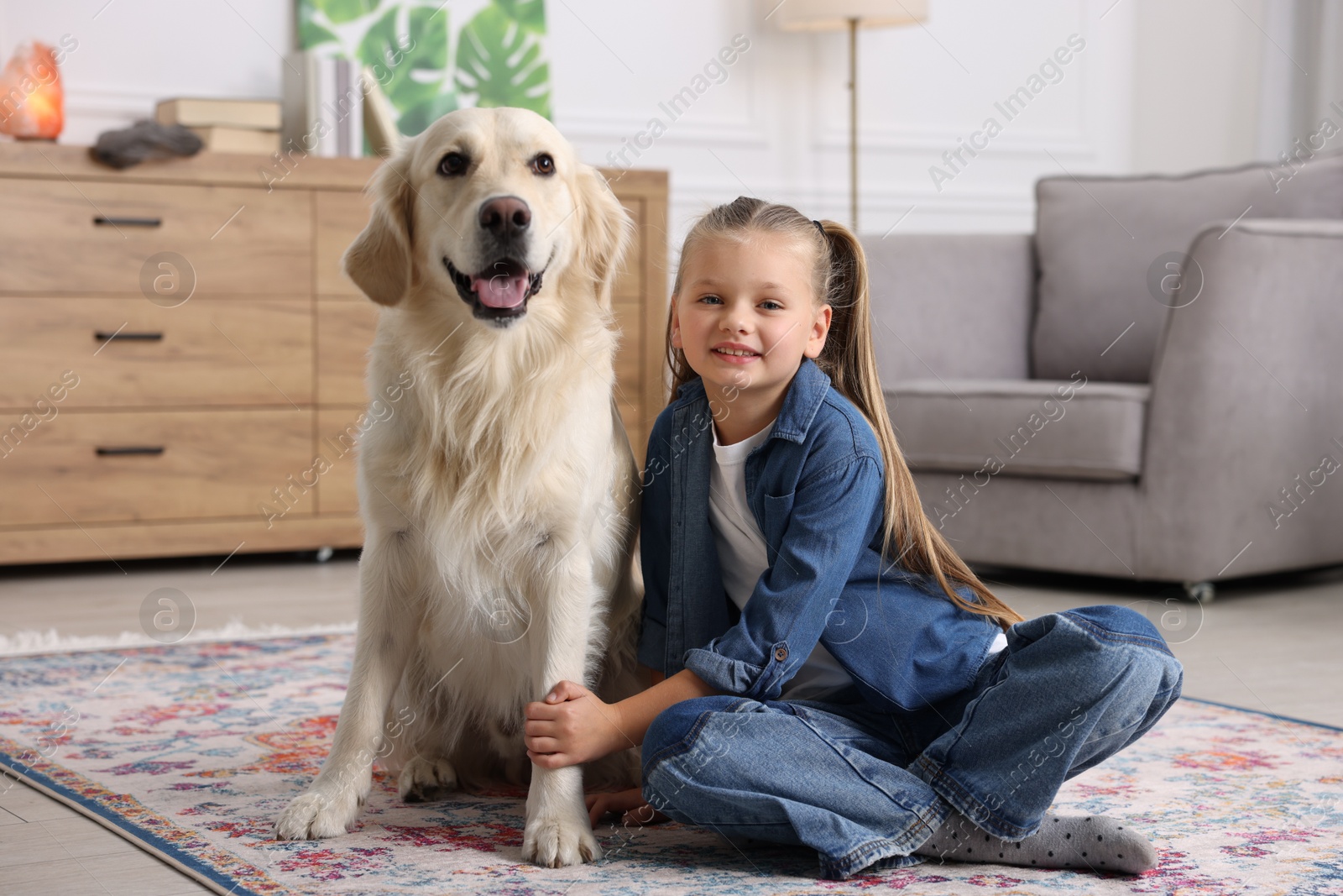 Photo of Girl with her cute Golden Retriever dog on rug at home