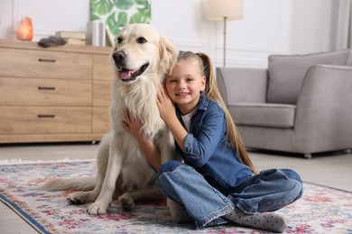 Girl with her cute Golden Retriever dog on rug at home