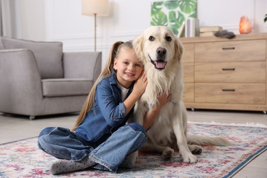 Photo of Girl with her cute Golden Retriever dog on rug at home