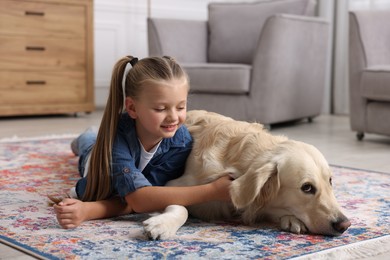 Girl with cute Golden Retriever dog lying on rug at home