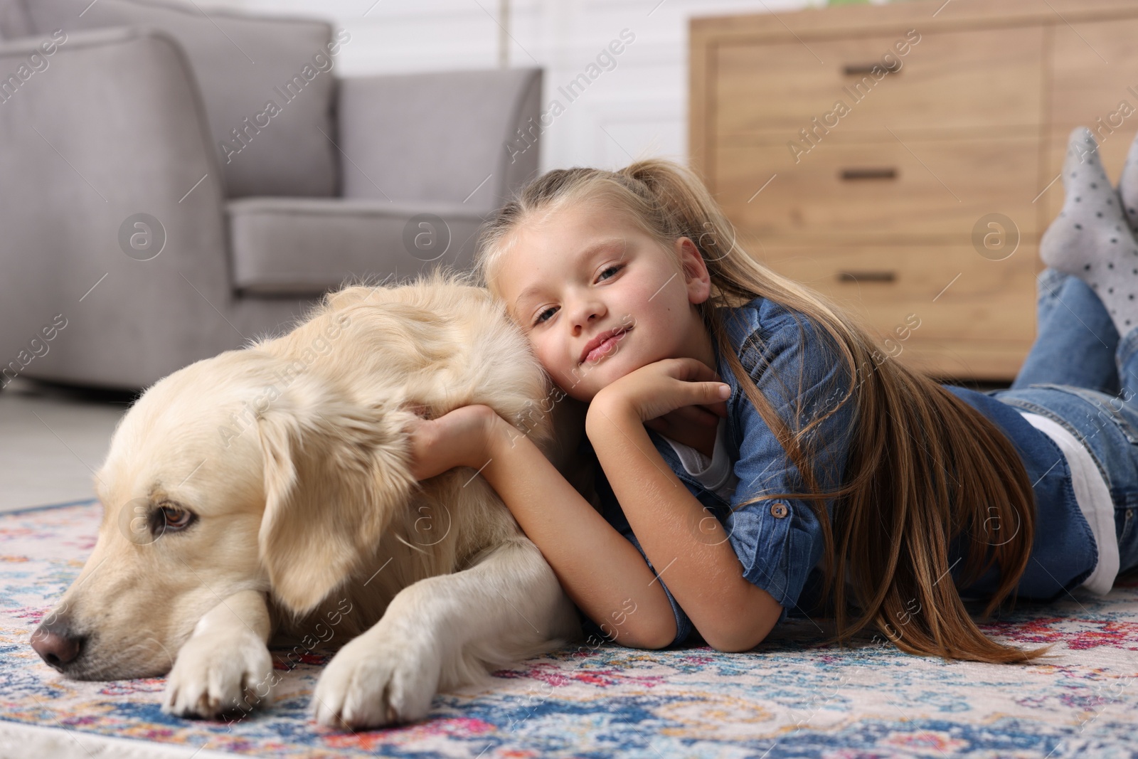 Photo of Girl with cute Golden Retriever dog lying on rug at home