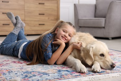 Girl with cute Golden Retriever dog lying on rug at home