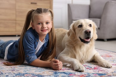 Girl with cute Golden Retriever dog lying on rug at home