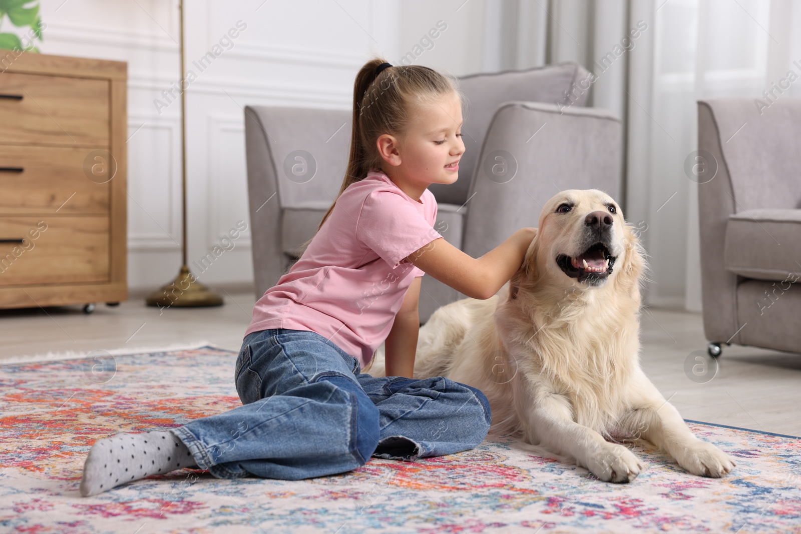 Photo of Girl with her cute Golden Retriever dog on rug at home