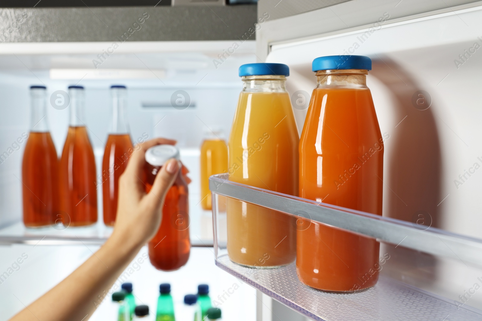 Photo of Woman taking bottle with drink from refrigerator, closeup