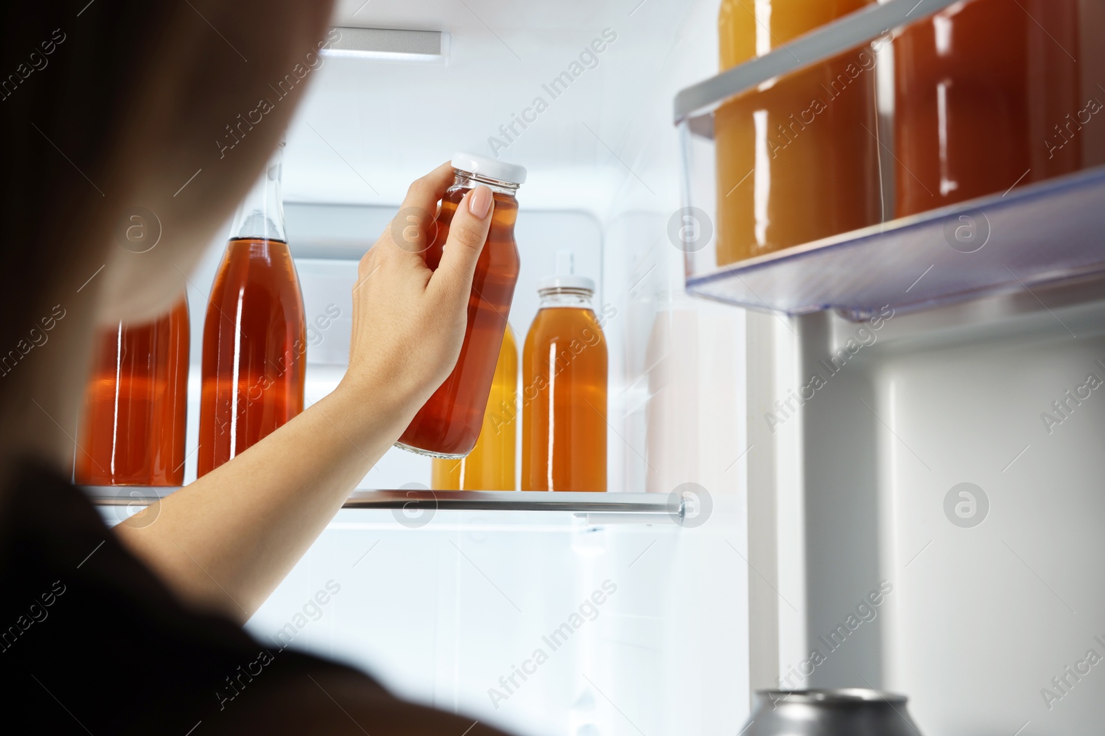 Photo of Woman taking bottle with drink from refrigerator, closeup