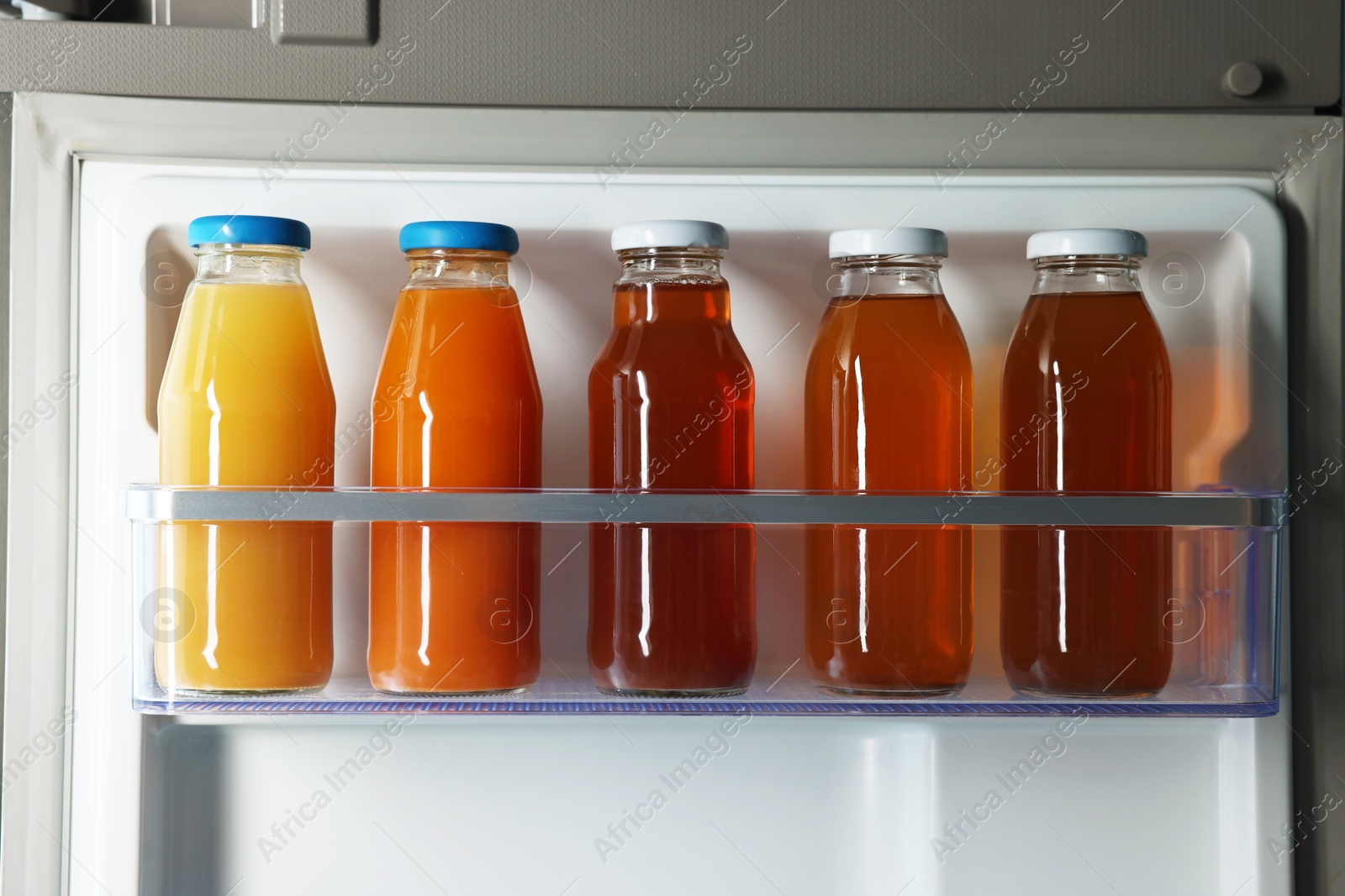 Photo of Many bottles of juice in refrigerator, closeup