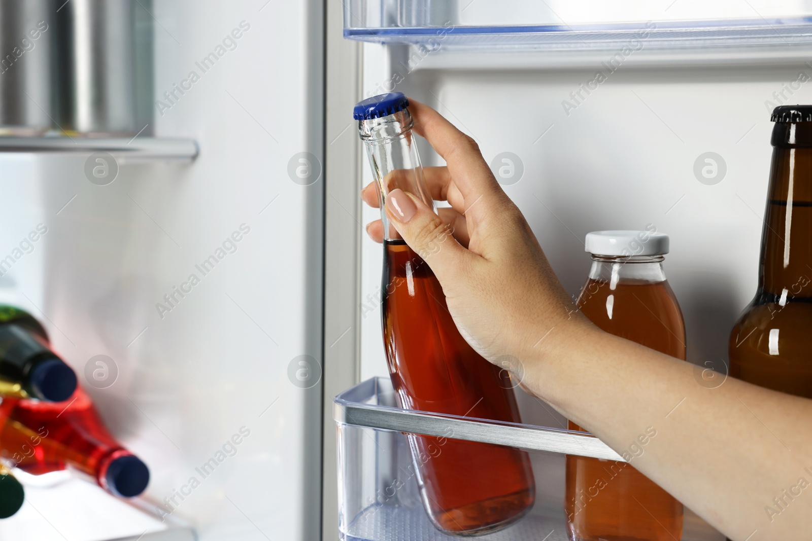 Photo of Woman taking bottle with drink from refrigerator, closeup