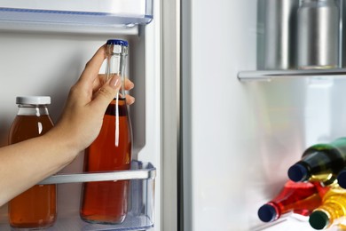 Photo of Woman taking bottle with drink from refrigerator, closeup