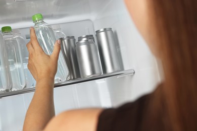 Photo of Woman taking bottle of water from refrigerator, closeup