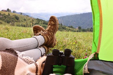 Photo of Woman wearing trekking shoes and lying in tent outdoors, closeup