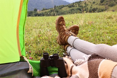 Photo of Woman wearing trekking shoes and lying in tent outdoors, closeup