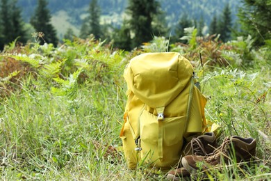 Photo of Backpack and trekking shoes on green grass outdoors