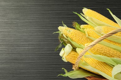 Photo of Many fresh ripe corncobs with green husks on wooden table, top view. Space for text