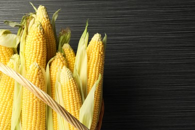 Photo of Many fresh ripe corncobs with green husks on wooden table, top view. Space for text