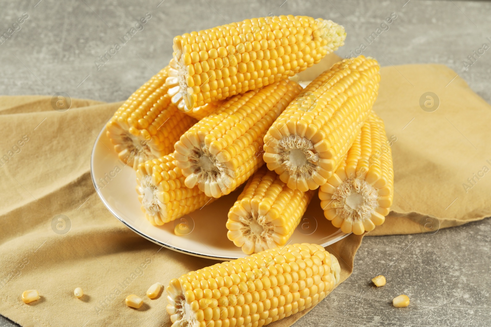 Photo of Halves of fresh ripe corncobs on grey table