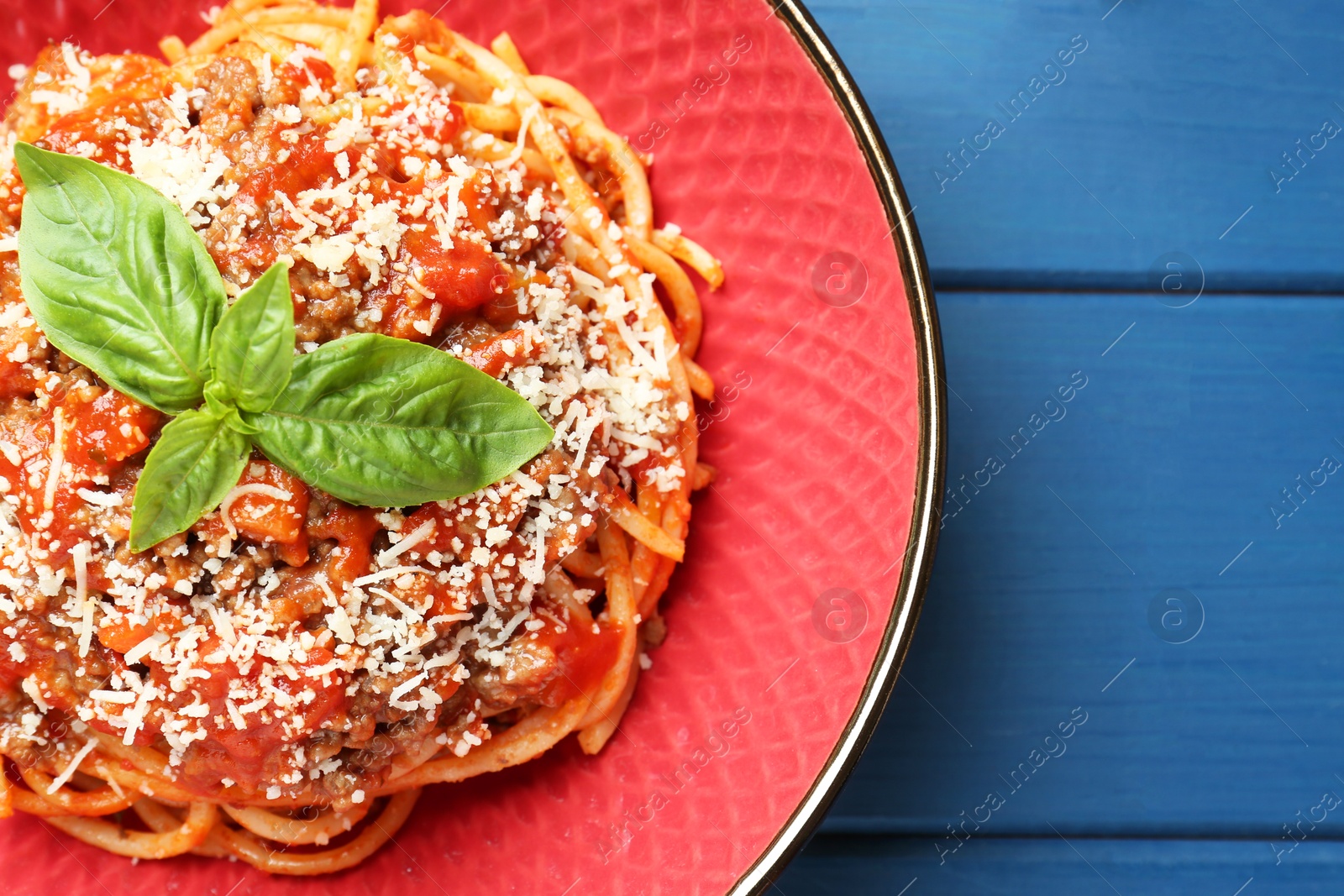 Photo of Delicious pasta bolognese with basil on blue wooden table, top view