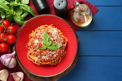 Photo of Delicious pasta bolognese with basil served on blue wooden table, top view. Space for text